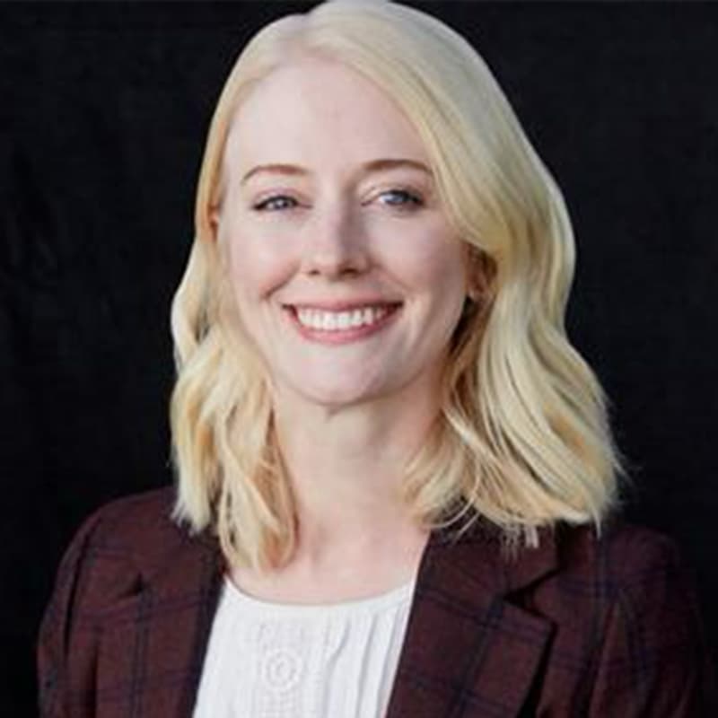 Headshot of Kelly Delaney, who is smiling and has shoulder length blonde hair. She wears a maroon blazer and white blouse.