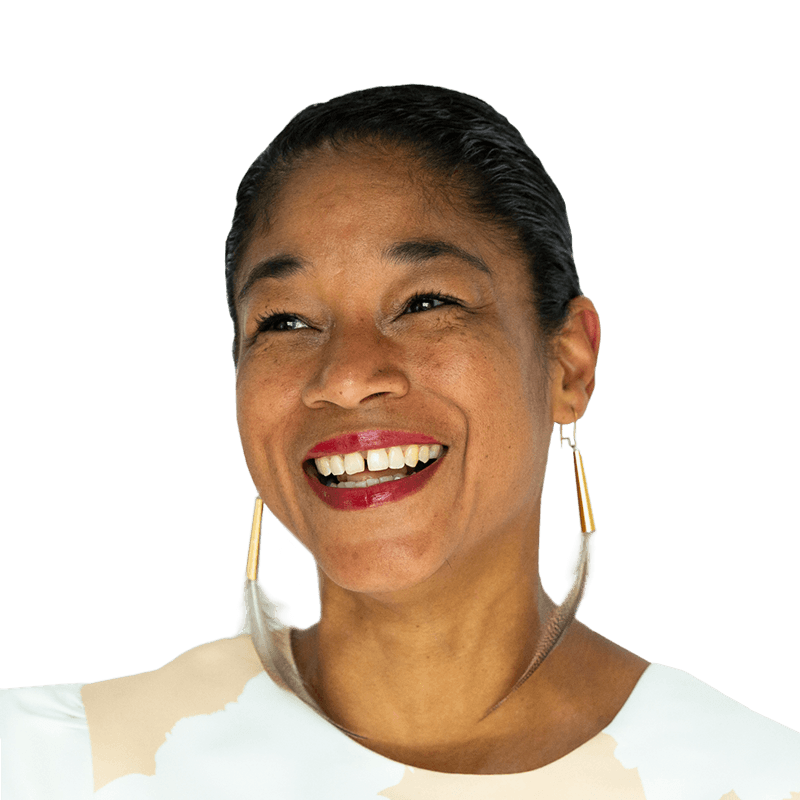 Headshot of Natalie Bomberry, who is smiling with her mouth open. She wears red lipstick, her hair is pulled back into a ponytail and she is wearing feather earrings.